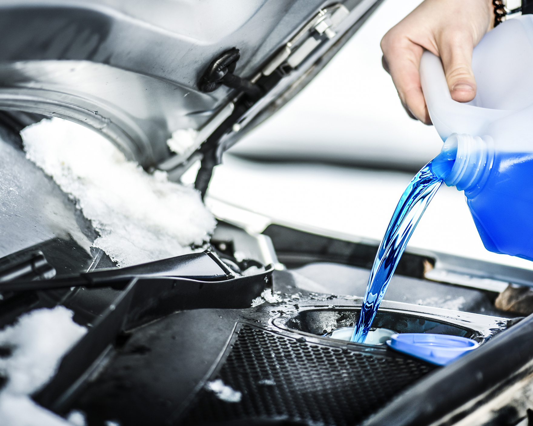 Pouring antifreeze liquid for washing car screen.